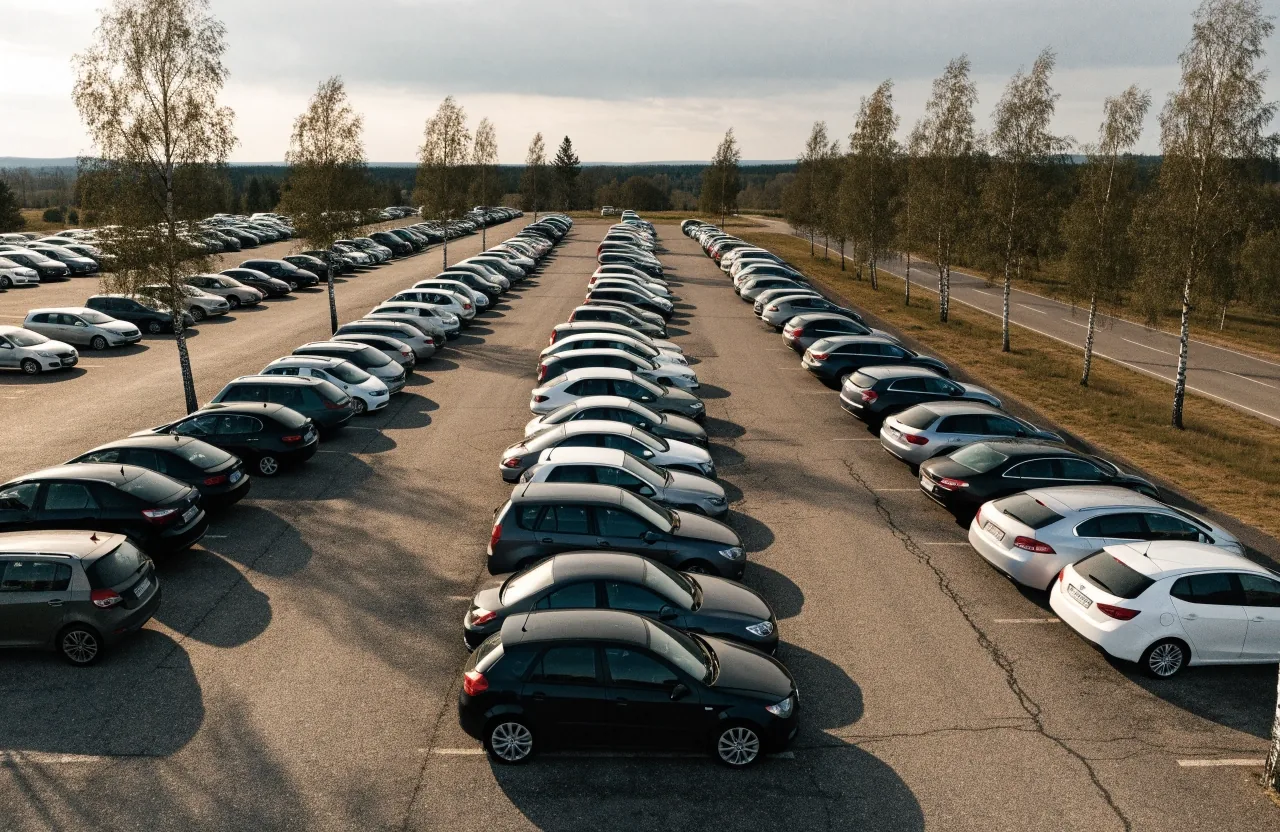 Suomalaisia henkilöautoja rivissä pysäköintialueella aamun valossa
